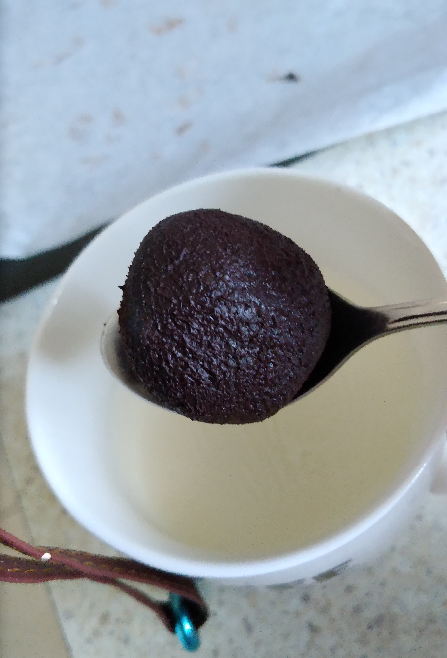 Ball of tablea chocolate being added to a mug of hot milk